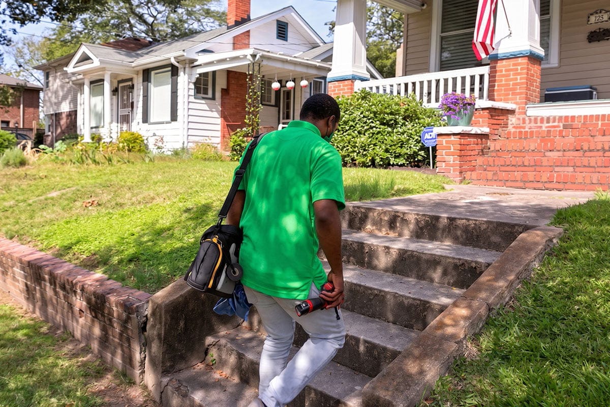 Worleys technician carrying a tool bag walking up to a customer's home