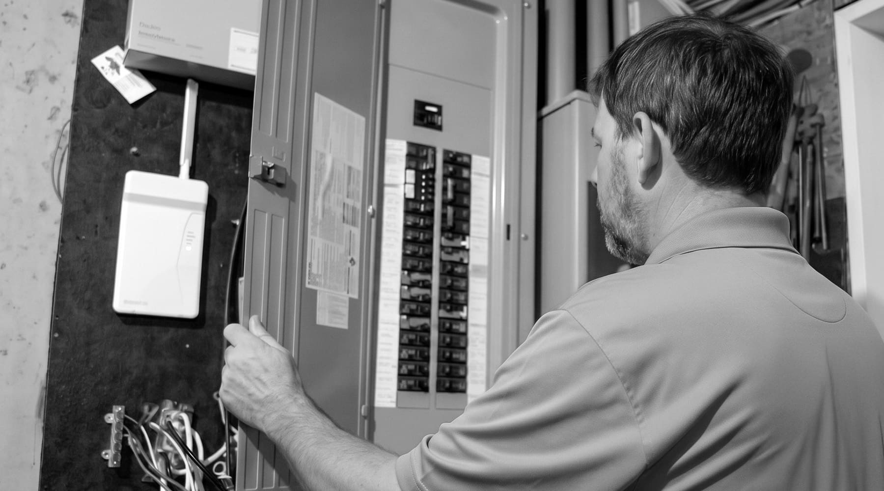Worley's technician swinging open a modern breaker panel door in a Hampton Roads utility room.